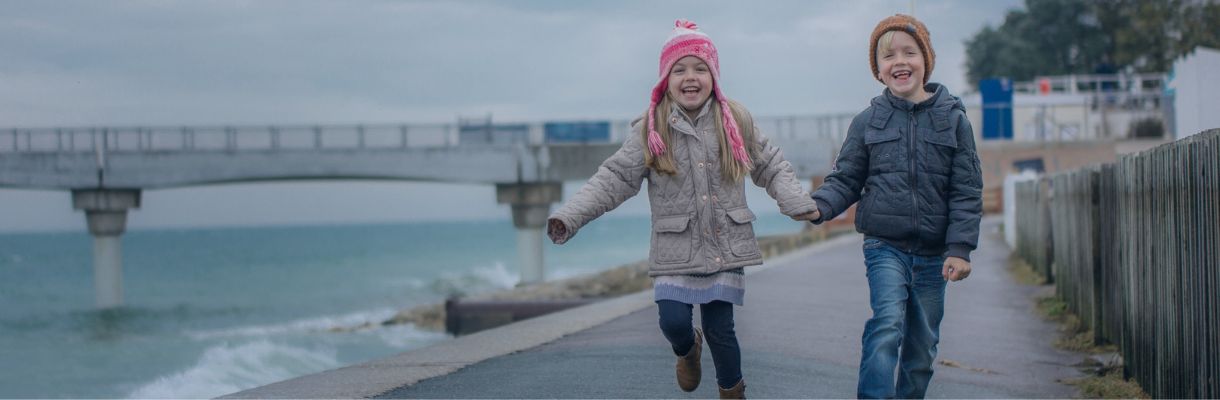 Children holding hands running and smiling